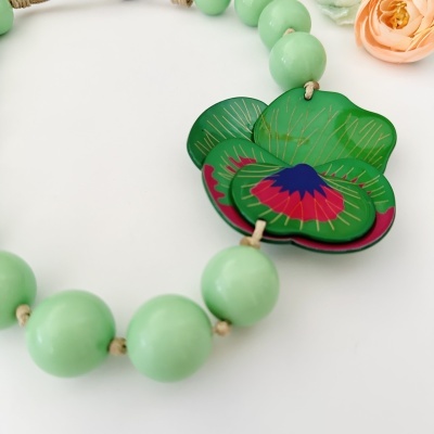 Colar com contas verdes redondas e pingente floral decorado