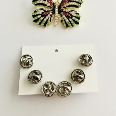 Broche borboleta colorida com strass e fechos metálicos sobre cartolina branca