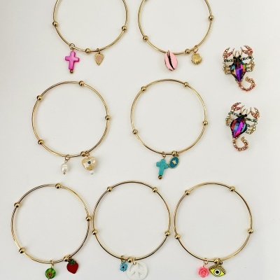 Seis pulseiras douradas com diferentes pendentes e dois pares de brincos coloridos em forma de escorpião