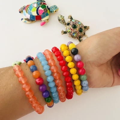 Pulseiras coloridas no pulso e broches de tartarugas coloridas em fundo branco
