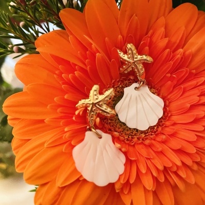 Brincos pendentes estrelas do mar douradas e conchas brancas na flor laranja