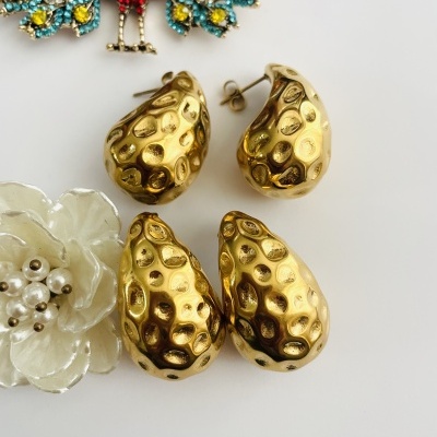 Brincos dourados texturizados junto com flor de esmalte e broche colorida