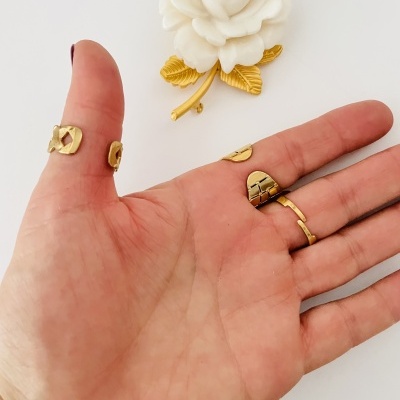 Mão com dois anéis dourados e flor branca decorativa ao fundo