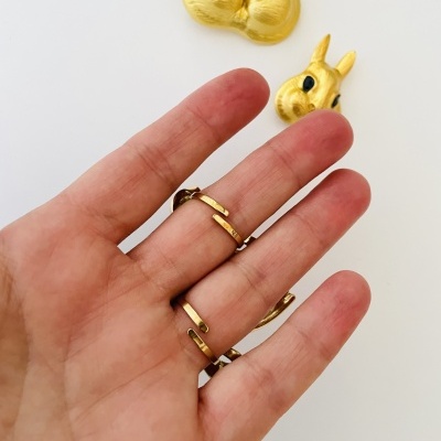 Mão com anéis dourados minimalistas e desenhos dourados de coelhos ao fundo