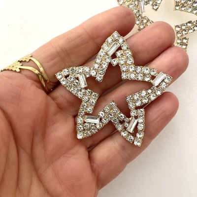 Brincos estrela com pedras brilhantes sobre mão humana