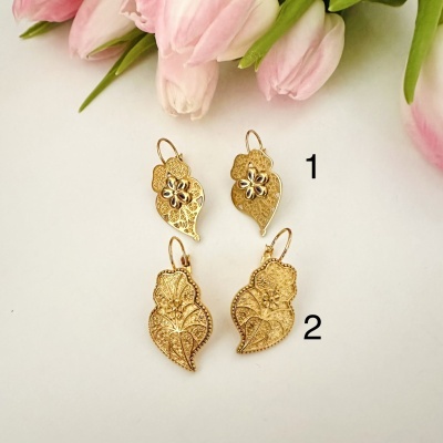 Dois pares de brincos dourados com detalhes florais e flores cor-de-rosa no fundo