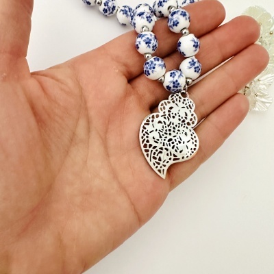 Colar com contas esféricas brancas e azuis e pendente metálico prateado decorativo na mão