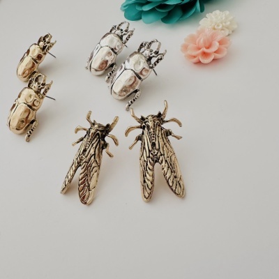 Brincos em forma de insetos dourados e prateados com flores decorativas coloridas