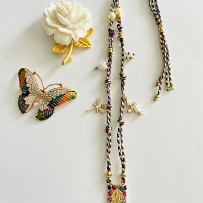Dois alfinetes decorativos e um colar com cordão trançado multicolorido e pingente dourado
