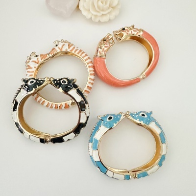 Quatro brincos coloridos com cabeças de cavalo douradas e detalhes em azul, preto, branco e coral