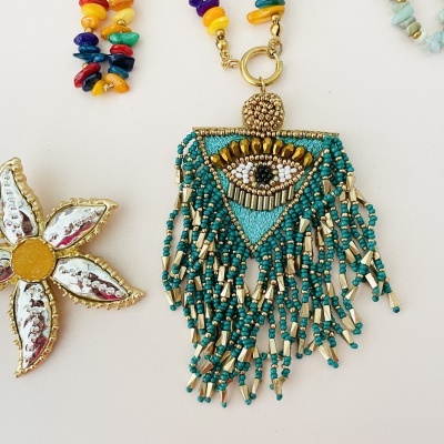 Colar com pendente de miçangas azuis, douradas e brancas em forma de olho com franjas