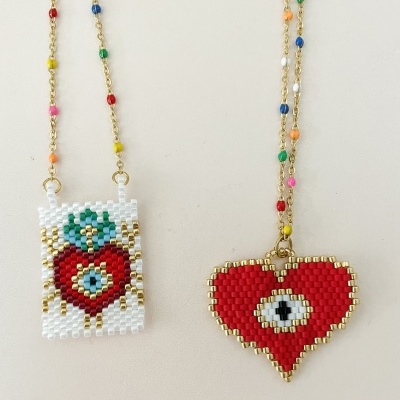 Dois colares com pendentes em forma de coração feitos de pequenas contas coloridas e correntes douradas com contas coloridas.
