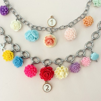 Duas pulseiras prateadas com elos grandes e pendentes coloridos em forma de flores