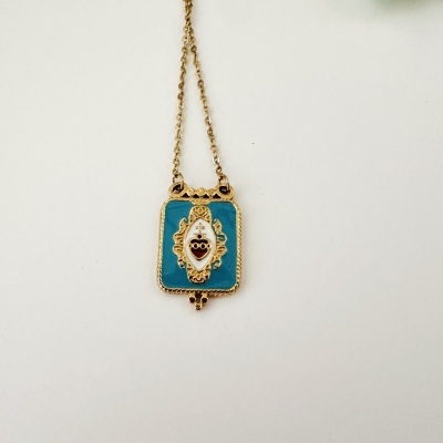 Colar com pendente retangular com fundo azul e coração vermelho com detalhes dourados.