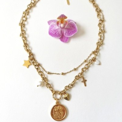 Colar dourado com medalha, cruz, estrela, coração e pérola, e uma flor orquídea roxa