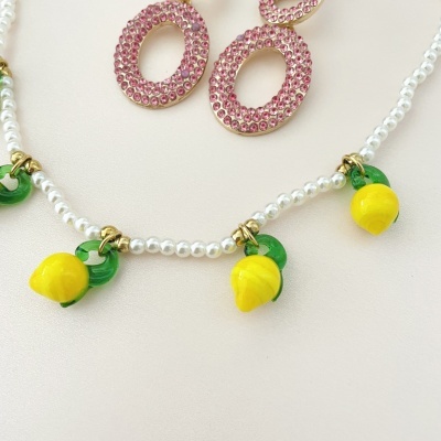 colar com pendentes amarelos de limão e brincos ovais rosa com pedras
