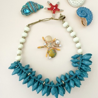 Colar azul com contas em forma de conchas e broche de estrela do mar com pérolas
