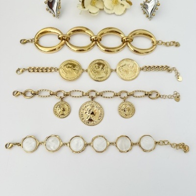 Conjunto de joias douradas com pulseiras e brincos flor e coração sobre fundo branco.