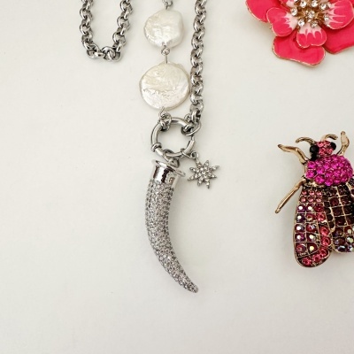 Colar com pendente de dente cravejado de cristais e estrela, e brincos em forma de flor vermelha e inseto cor de rosa
