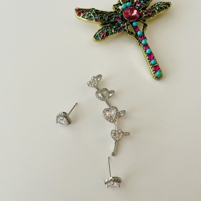 Broche libélula colorida e brincos prateados com corações sobre fundo branco