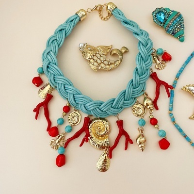 Colar azul com pendentes dourados e vermelhos e broche dourado de peixe