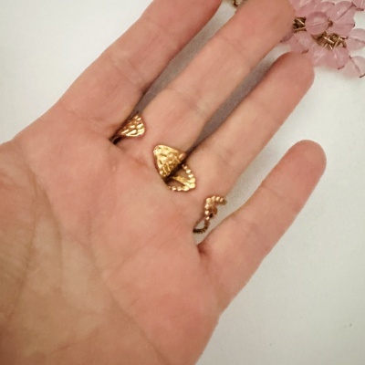 Brinco dourado triangular martelado na mão com pedras rosas ao fundo
