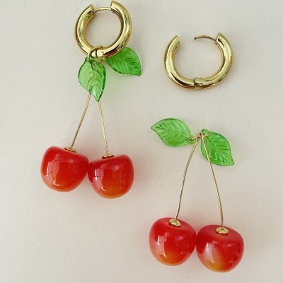 Brincos dourados com pendentes de cerejas vermelhas e folhas verdes