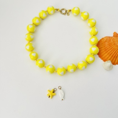 Colar amarelo com corações brancos, pendentes e conchas ao lado