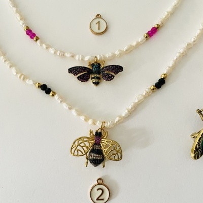 Dois colares com pendentes de abelhas coloridas e etiquetas numeradas