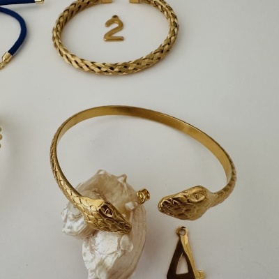Duas pulseiras douradas e dois números dourados 2 e 4 numa superfície branca