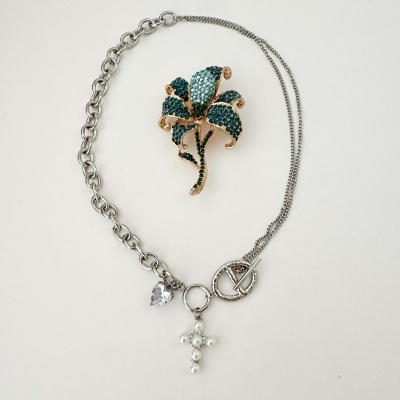 Colar prateado com cruz de pérolas e coração de cristal, e broche flor azul e dourado