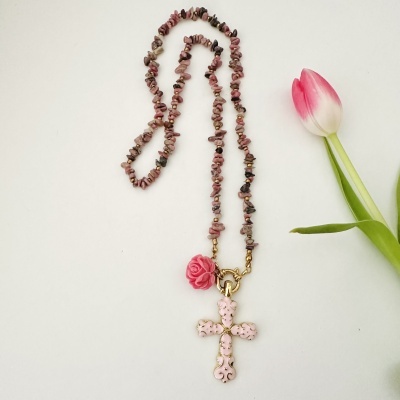 Colar rosa com pendentes de cruz e flor perto de tulipa rosa