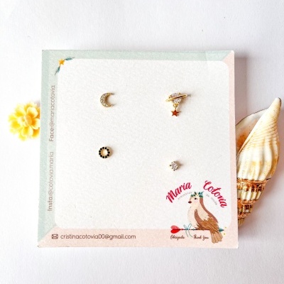 Conjunto de brincos dourados com vários motivos sobre cartolina ilustrada