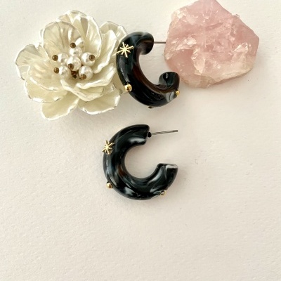 Brincos argola preto e branco com detalhes dourados, flor branca e cristal rosa.