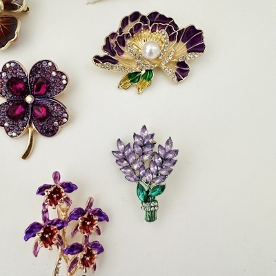 Broches florais em tons roxos com detalhes brilhantes e pérola