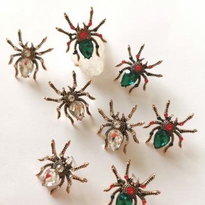 Brincos em forma de aranha com pedras coloridas sobre fundo branco
