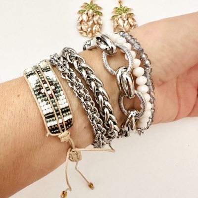 Pulseiras variadas com miçangas e elos metálicos no pulso em fundo branco