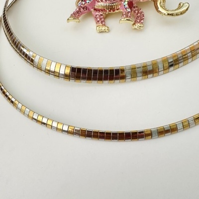 Colar metálico prateado e dourado com pendente de elefante rosa com pedras brilhantes.