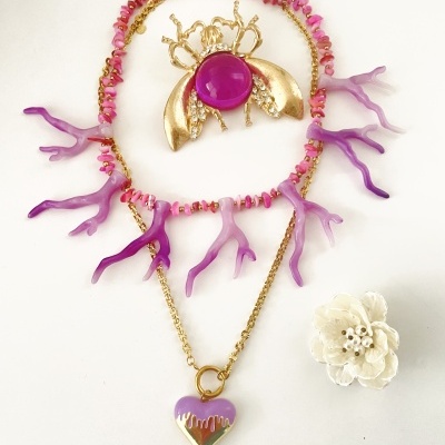 Colares com pedras rosa e pendentes roxos, broche dourado com pedra roxa e flor branca de tecido