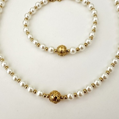 Colar e pulseira com contas brancas e douradas sobre fundo branco
