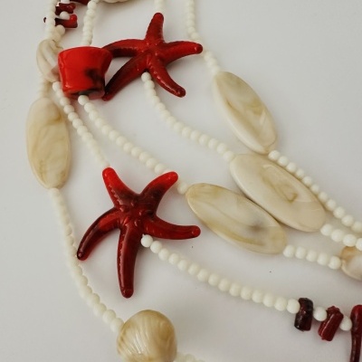 Colar com contas brancas e pendentes de conchas e estrelas do mar vermelhas