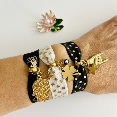 Pulseiras de tecido com pendentes dourados no pulso