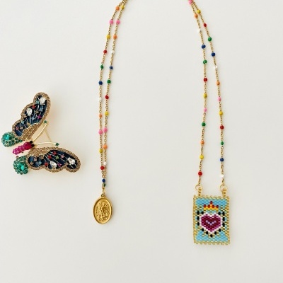 Colar com contas coloridas e medalhões dourados e presilha de cabelo de borboleta com pedrarias coloridas