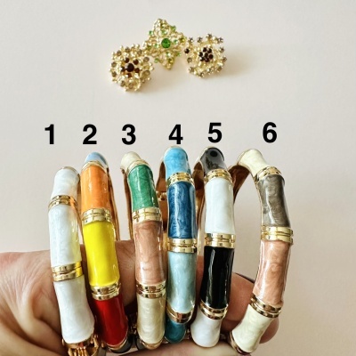 Seis pulseiras esmaltadas numeradas e três brincos dourados com pedras no fundo