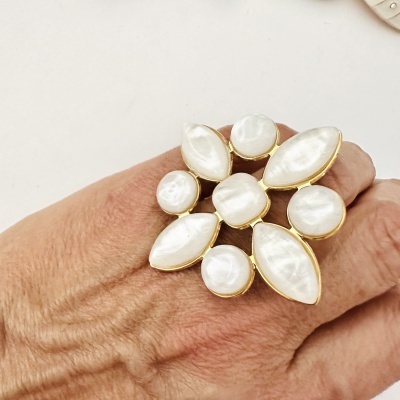 Anel dourado com pedras brancas irregulares em mão de pele clara