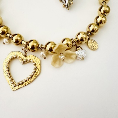 Pulseira dourada com vários pendentes decorativos incluindo coração e flores.