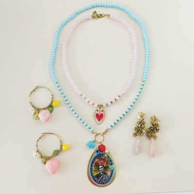 Conjunto de bijuteria com colares e brincos em tons azul, rosa e dourado sobre fundo branco