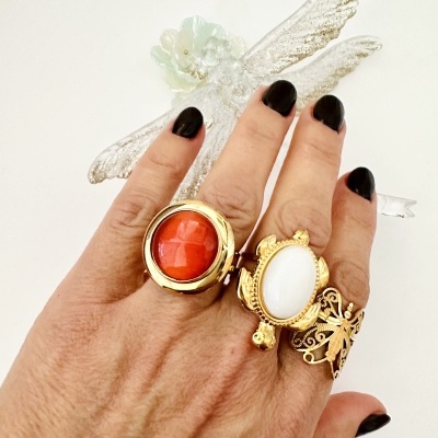 Mão com três anéis dourados com pedras e um com design de borboleta