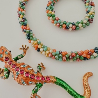 Colar e pulseira coloridos com contas facetadas e broche em forma de lagarto com pedras