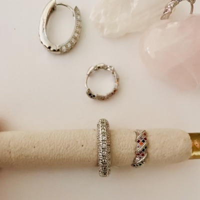 Joias de prata com pedras coloridas e brilhantes sobre fundo branco